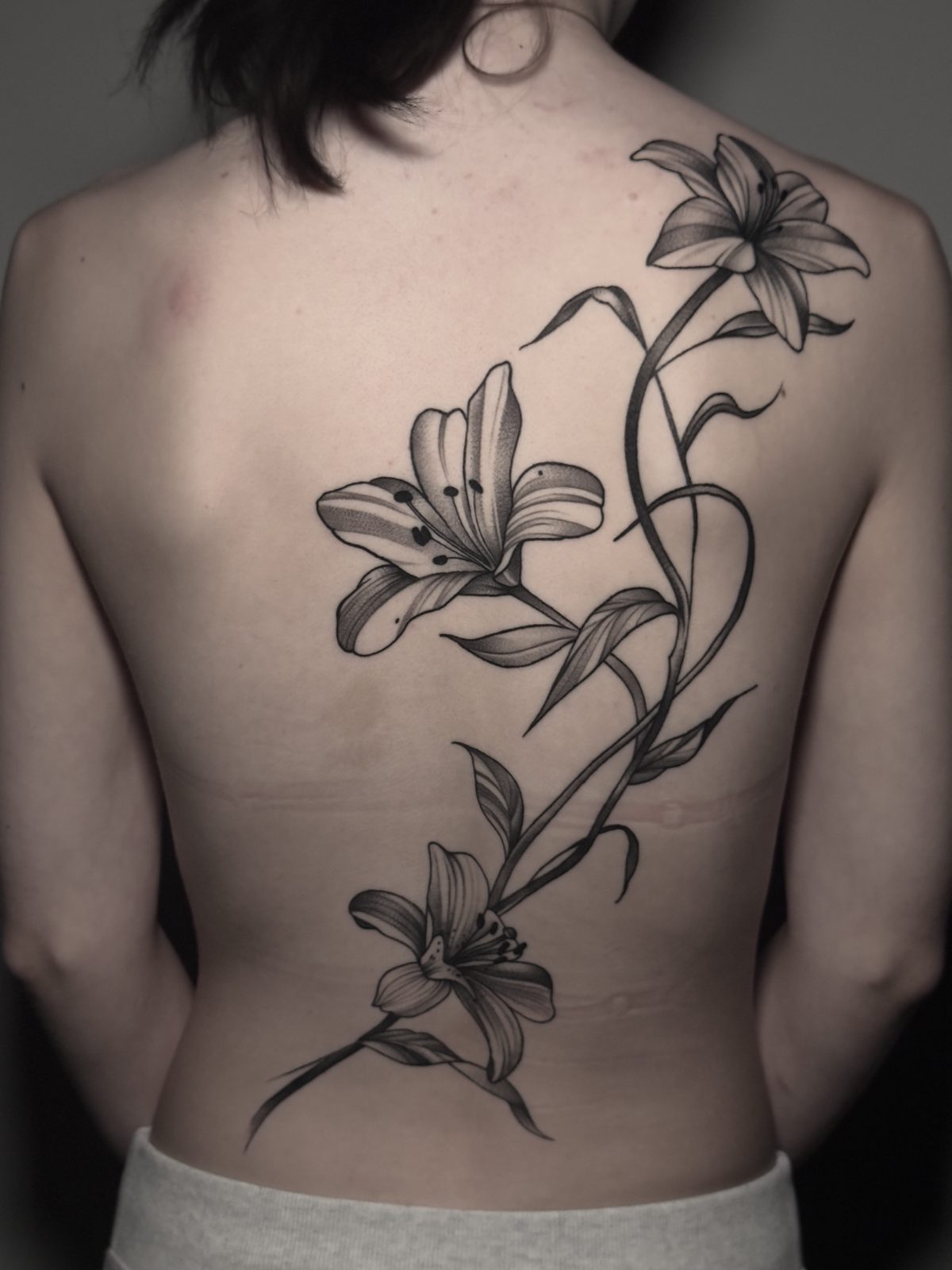 Lilies climbing the spine in fine black and grey