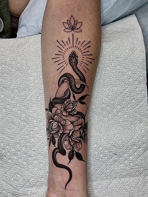Snake through florals beneath a lotus, forearm