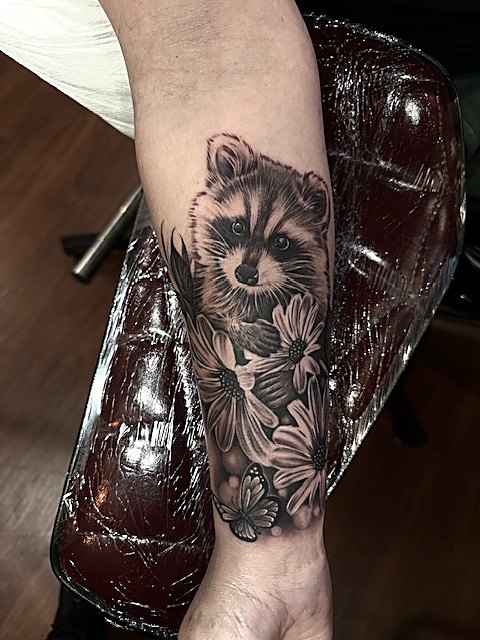 Raccoon among florals, forearm