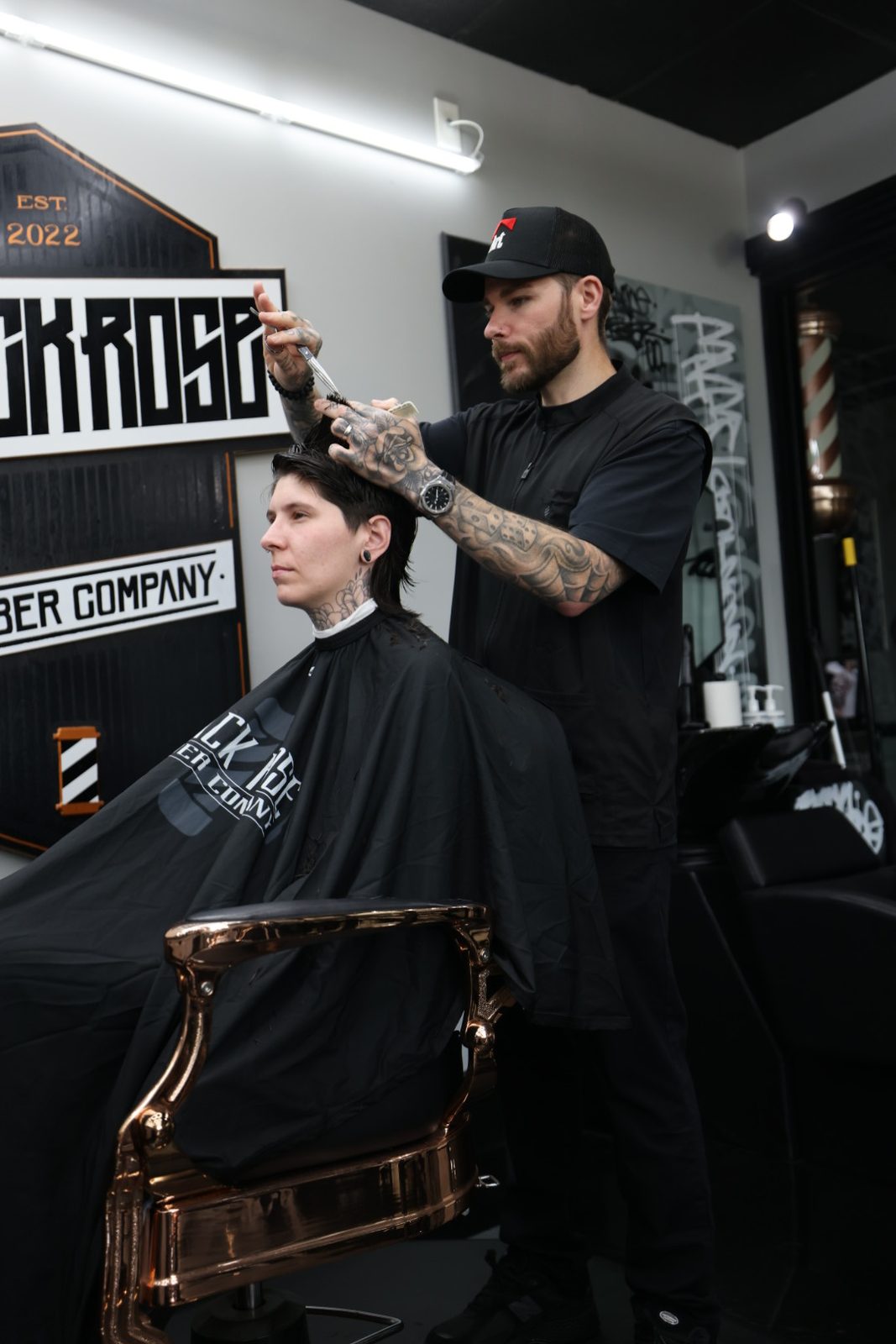 Derek at the chair, under the shop sign