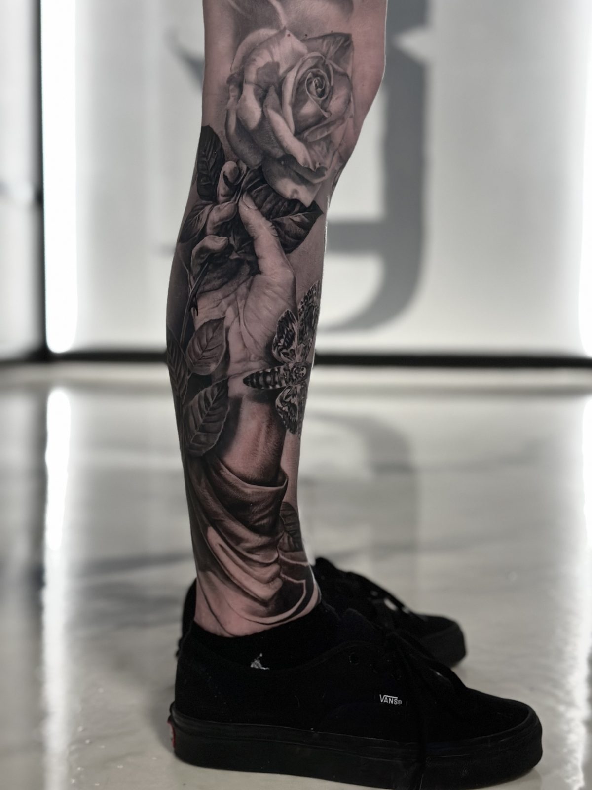 Rose and figures running down the shin